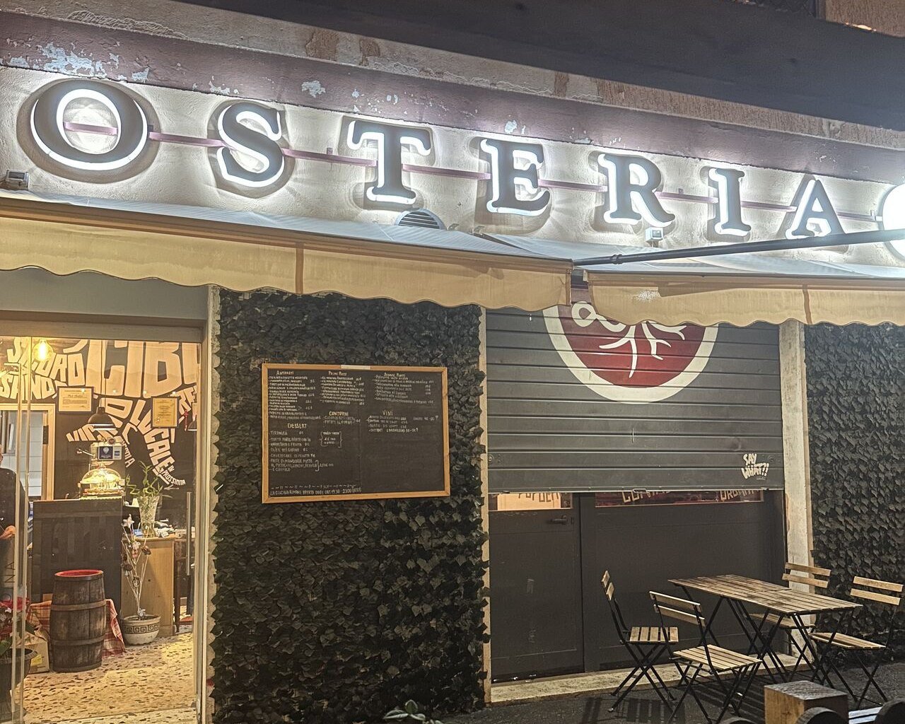Insegna dell'osteria accesa la sera, cucina romana a Centocelle